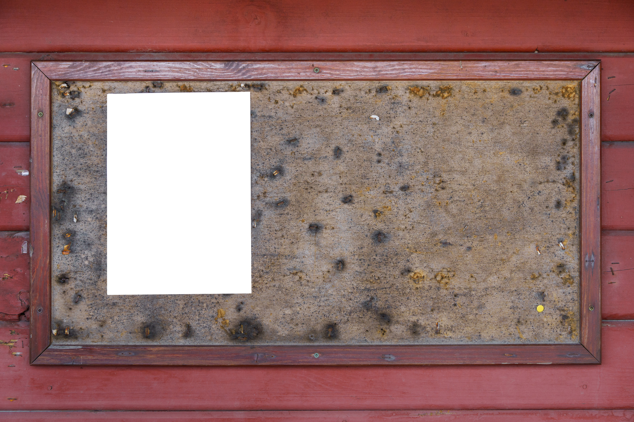 Old bulletin board with an empty white note on red wooden wall.